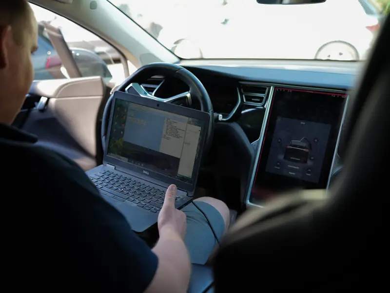 Diagnostyka komputerowa Tesli - mechanik z laptopem podłączonym do auta
